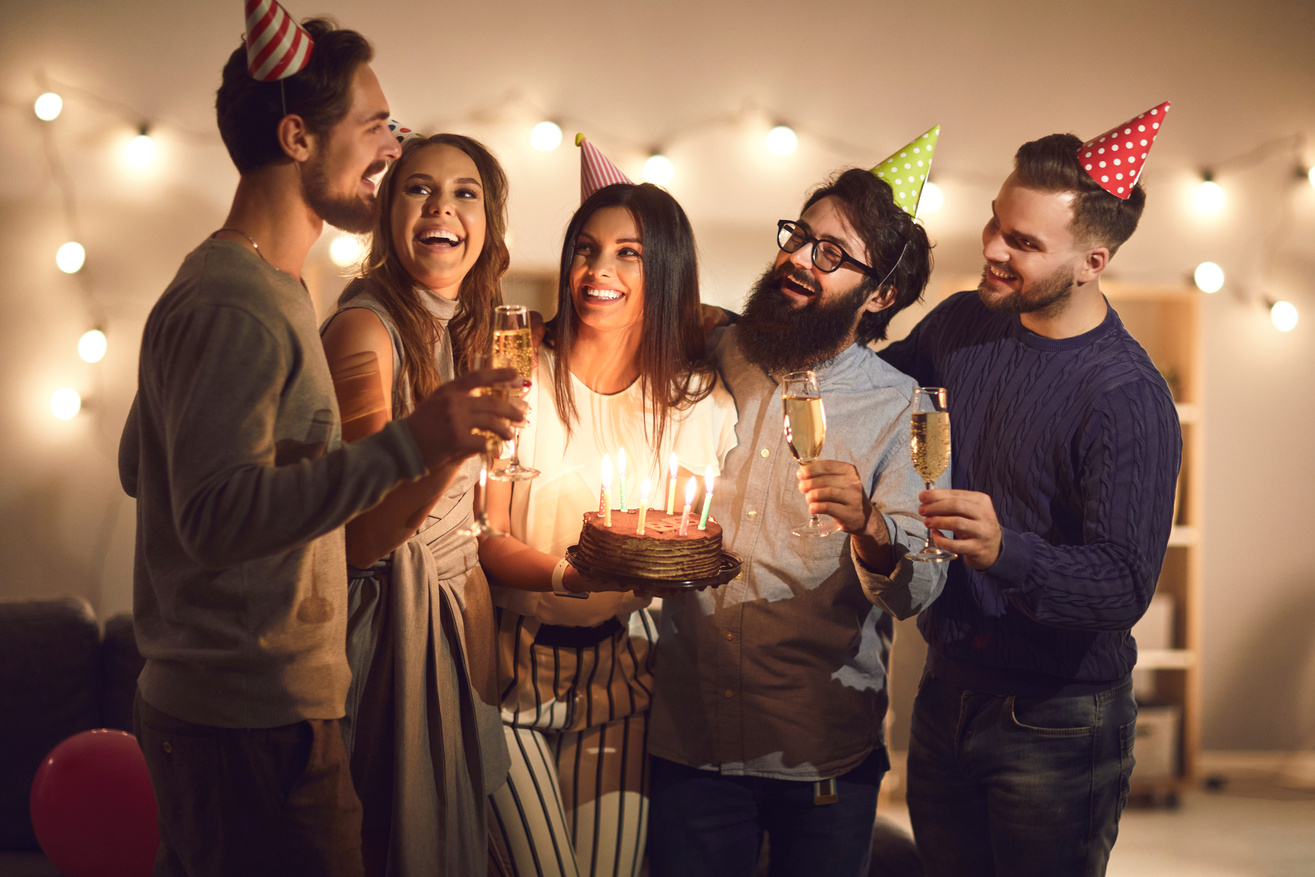 Group of Smiling Friends in Decorative Caps Having Fun during Birthday Party